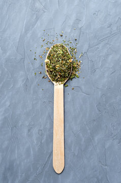 Dried herbs and spices in a wooden spoon on a gray concrete background. Provencal herbs, basil, rosemary, oregano, marjoram, thyme, sage, mint, thyme.
