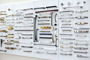 Big selection of handles cabinets parts on a white background shop window. samples of Metal and Stainless Steel handle styles on wooden kitchen cabinet with different Stainless Steel handles