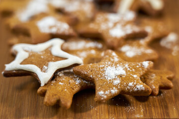 Ginger biscuits with sugar powder on a wooden board.