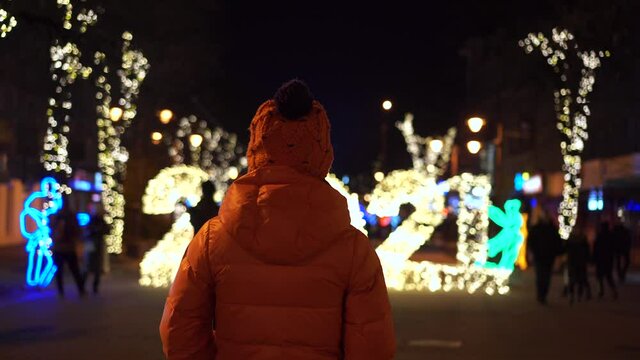 Rear view of a girl looking at the Christmas lights in the form of 2021