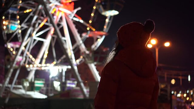 Bottom view of Illuminated Ferris Wheel with a silhouette of a girl. Winter mood