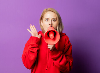 Obraz premium Blonde girl in red sweatshirt on purple background