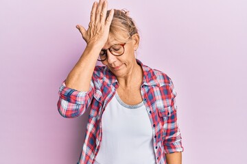 Middle age blonde woman wearing casual clothes and glasses surprised with hand on head for mistake,...