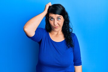 Plus size brunette woman wearing casual blue shirt confuse and wonder about question. uncertain with doubt, thinking with hand on head. pensive concept.