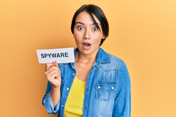 Beautiful young woman with short hair holding spyware text scared and amazed with open mouth for surprise, disbelief face