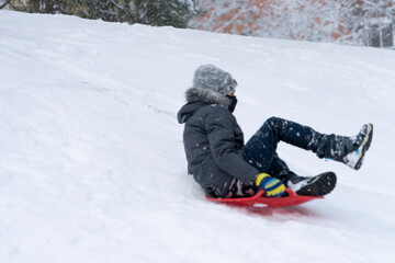 Boy enjoying a sleigh ride. Kid playing outdoors in snow