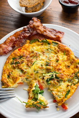 Omelette. Classic American brunch or breakfast menu item served at traditional American restaurant. Farm fresh eggs, cooked in butter with fresh vegetables pork, bacon, cheese and served with salad 