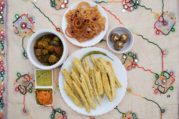 Uttarayan, maar sankranti, special food items from Gujarat fafda, faafda, jalebi, raw papaya salad, undhiyu and green chilly. for kite festival with traditional gujarat fabric background