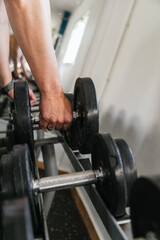 Fototapeta na wymiar Hand holding weight in the gym. Close up. Focus is on hand. GYM concept