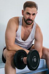 Fototapeta na wymiar Man making biceps with a dumbbell. Fitness in gym, sport and healthy lifestyle concept