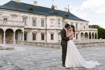 Obraz premium Bride and groom kissing each other in the background of the old palace