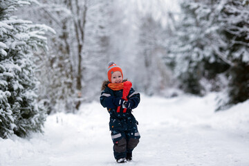 Fototapeta na wymiar Pretty toddler girl wearing winter clothes having fun outside in snowy day