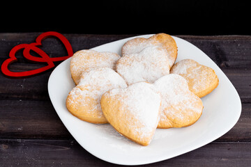 cookies for the Valentine's Day holiday, Heart-shaped cookies on a black background, on a white plate.