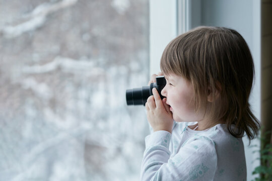 The baby takes pictures with a camera on a winter street. Selective focus. Copy space.