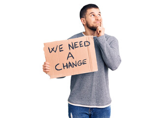 Young handsome man holding we need a change banner serious face thinking about question with hand...