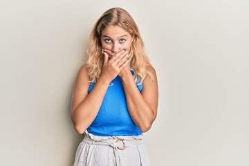Young blonde girl wearing casual clothes shocked covering mouth with hands for mistake. secret concept.