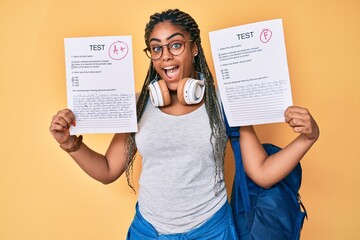 Young african american woman with braids showing failed and passed exam celebrating crazy and...