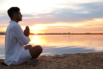 Fototapeta premium Man near river at sunset, space for text. Nature healing power