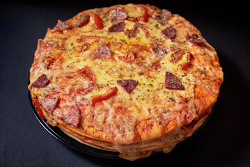 Italian Pizza Cake with four layers full of grilled salami, ham and moose sausage. Black background.