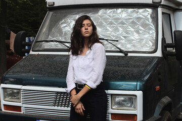A beautiful young girl stands near the car. Active rest and travel. Emotions.
