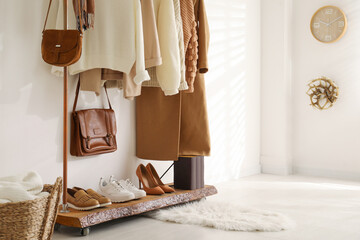 Rack with stylish shoes and women's clothes in dressing room. Modern interior design
