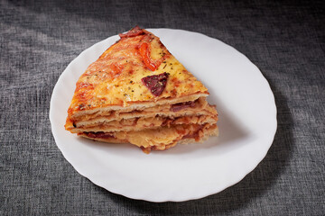 Italian Pizza Cake with four layers full of grilled salami, ham and moose sausage. Black background.
