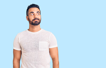 Young hispanic man wearing casual clothes smiling looking to the side and staring away thinking.