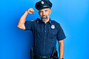 Middle age handsome man wearing police uniform strong person showing arm muscle, confident and proud of power