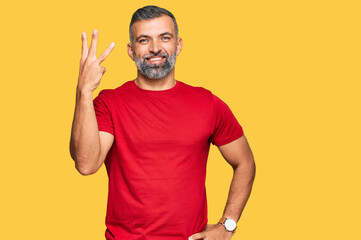 Middle age handsome man wearing casual clothes showing and pointing up with fingers number three while smiling confident and happy.