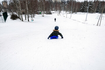 Fototapeta na wymiar The child is sledding down the hill. Downhill skiing in winter.