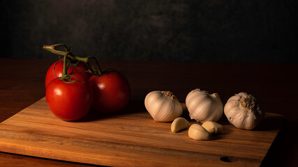 High Contrast of Tomatoes and Garlic on wood cutting board