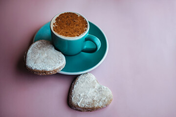 cup of fresh morning cappuccino sprinkled with cocoa powder on top and homemade ginger cookies in the shape of heart. on pink backdrop. concept of Valentine day and romantic breakfast.  Blogger style.