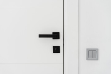 Light switch on the white wall near modern door