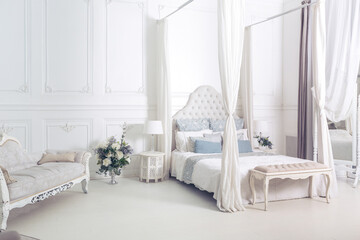 bright, clean stylish interior bedroom and living room with a large panoramic window. beautiful rich antique furniture. four-poster bed, a mirror and a sofa.