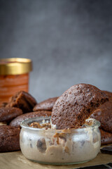 Close up of a fluffy chocolate brownie cookie placed inside a bowl of peanut butter ice cream. Healthy homemade gluten free chocolate chip cookies with an ice cream bucket in the background.
