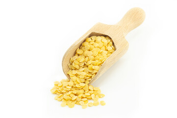Uncooked raw yellow lentil in wooden shovel isolated on white background, (Lens culinaris)