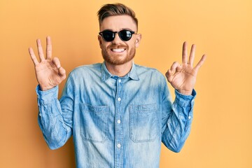 Naklejka premium Young redhead man wearing stylish sunglasses relax and smiling with eyes closed doing meditation gesture with fingers. yoga concept.
