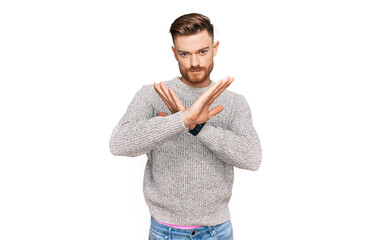 Young redhead man wearing casual winter sweater rejection expression crossing arms doing negative sign, angry face