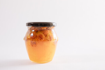 Small jar with honey and nuts. Glass jar with black lid on a white background