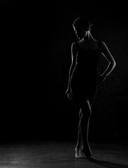 Dark silhouette of beautiful woman body on a dark background. Black and white photo.