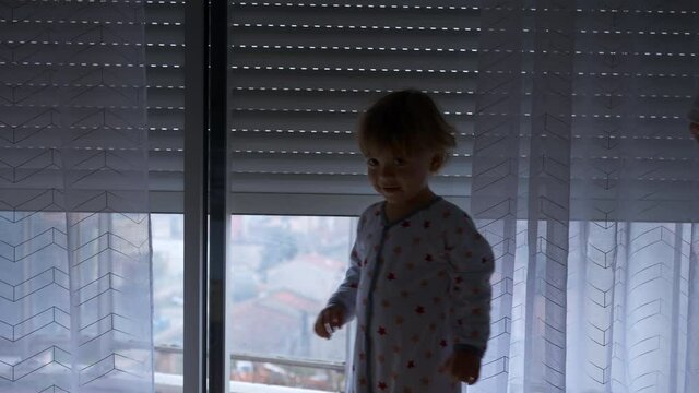 Baby toddler looking at automatic blinds going up, starting the day concept