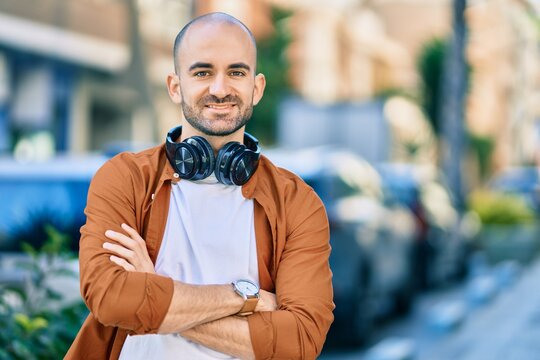 Young hispanic bald man smiling happy using headphones at the city