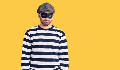 Young handsome man wearing burglar mask depressed and worry for distress, crying angry and afraid....