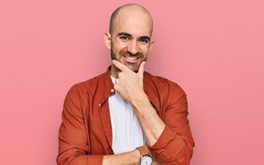 Young hispanic man wearing casual clothes looking confident at the camera smiling with crossed arms and hand raised on chin. thinking positive.