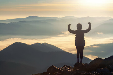 Silhouette of strong woman on mountain peak flexing her muscles.