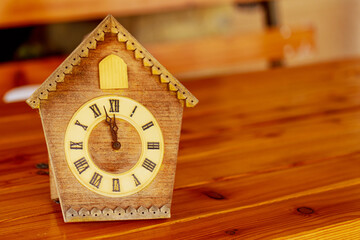 Retro cuckoo clock with Roman numerals on a wooden table.