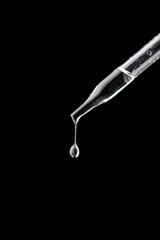 Glass pipette with drop on black background