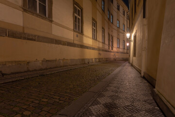 Fototapeta na wymiar .lit street lights and a cobbled street with cobblestones in the center of Prague at night