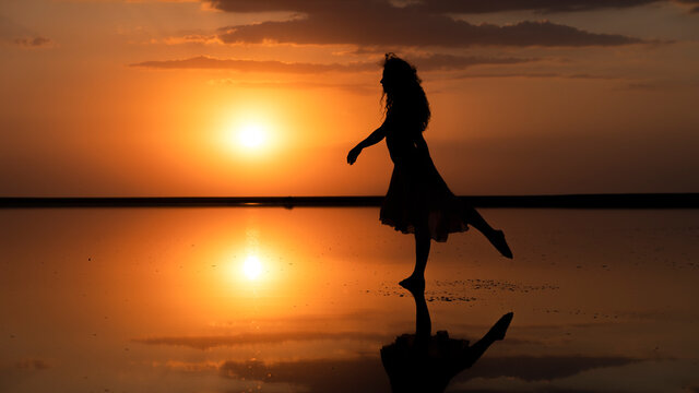 fabulous silhouette of a free girl on the background of a golden sunset in the ocean