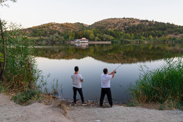 Fototapeta premium Back rear view of two fishermen in Eymir Lake, Ankara, Turkey